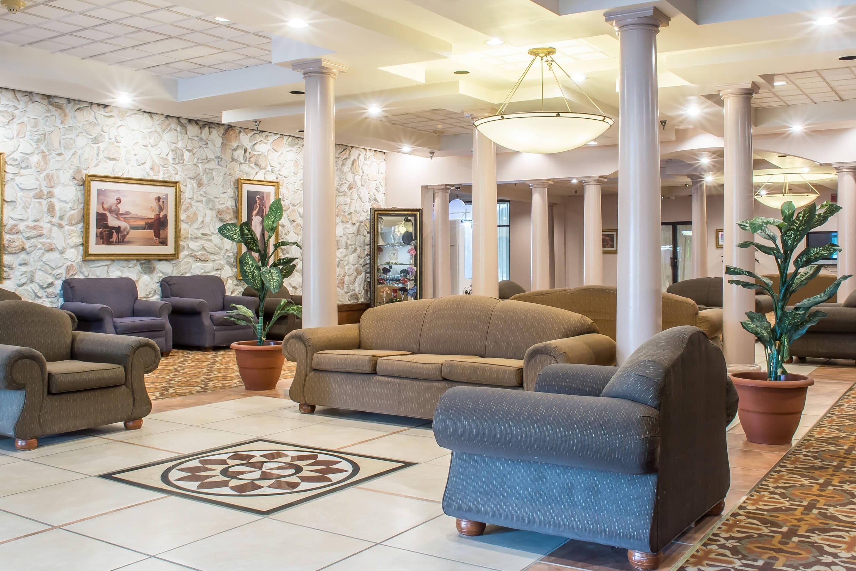 A lobby with multiple seating areas, stone walls, and large columns.