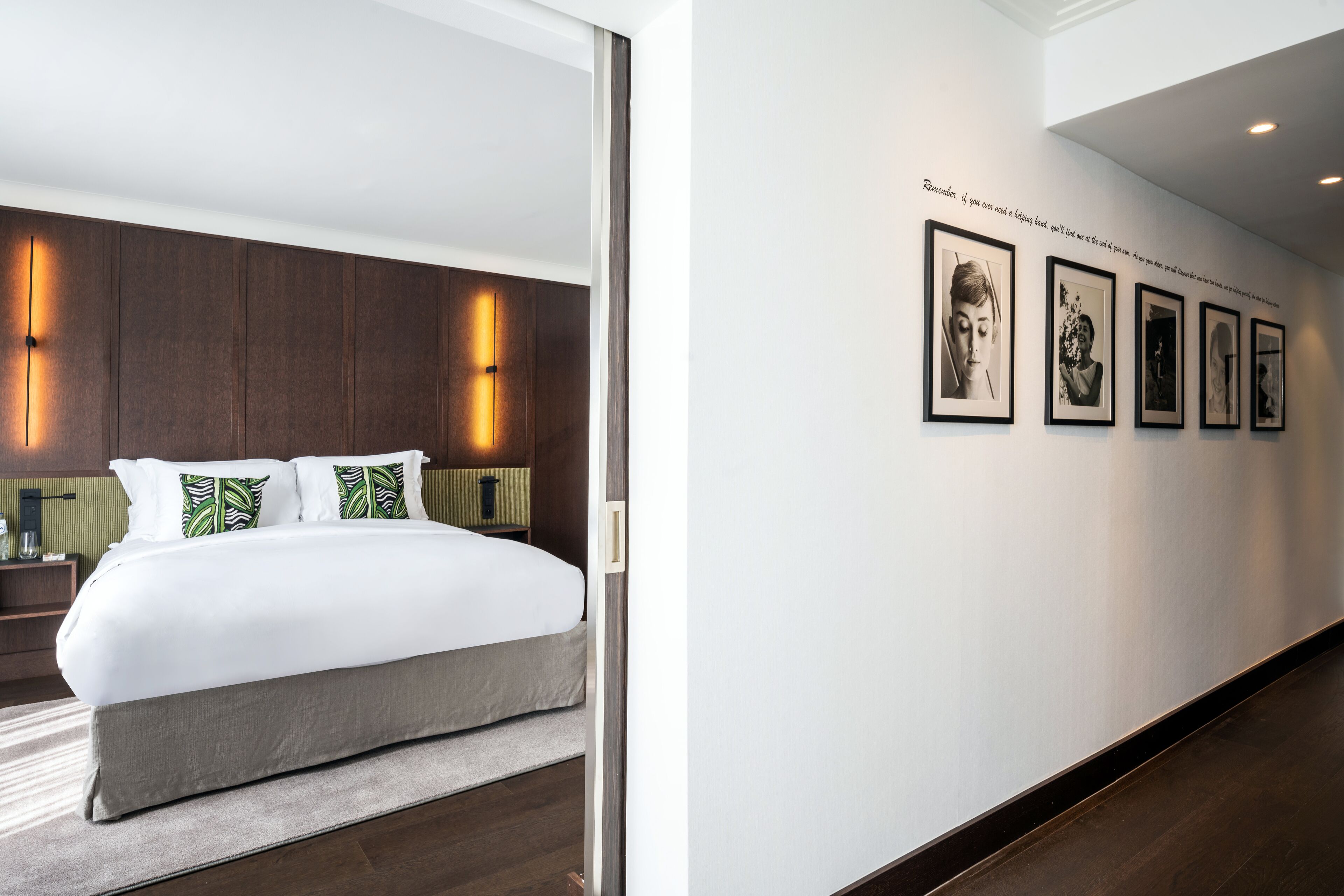 A modern hotel room with a large bed, a nightstand, and a wall-mounted light.