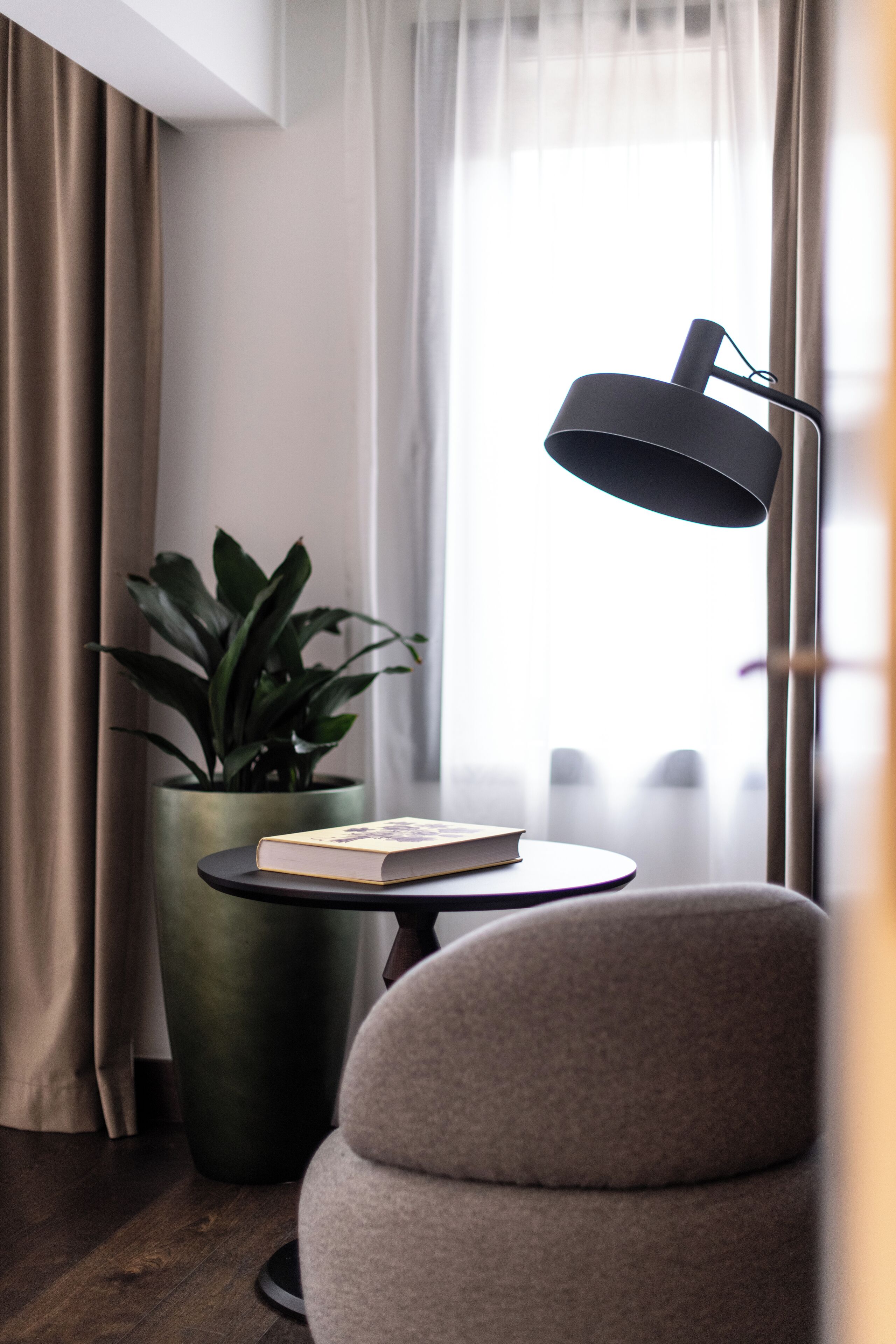 A modern room with a round table, a potted plant, a lamp, and a chair.