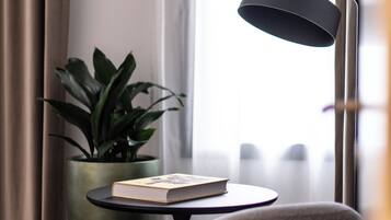 A modern room with a round table, a potted plant, a lamp, and a chair.
