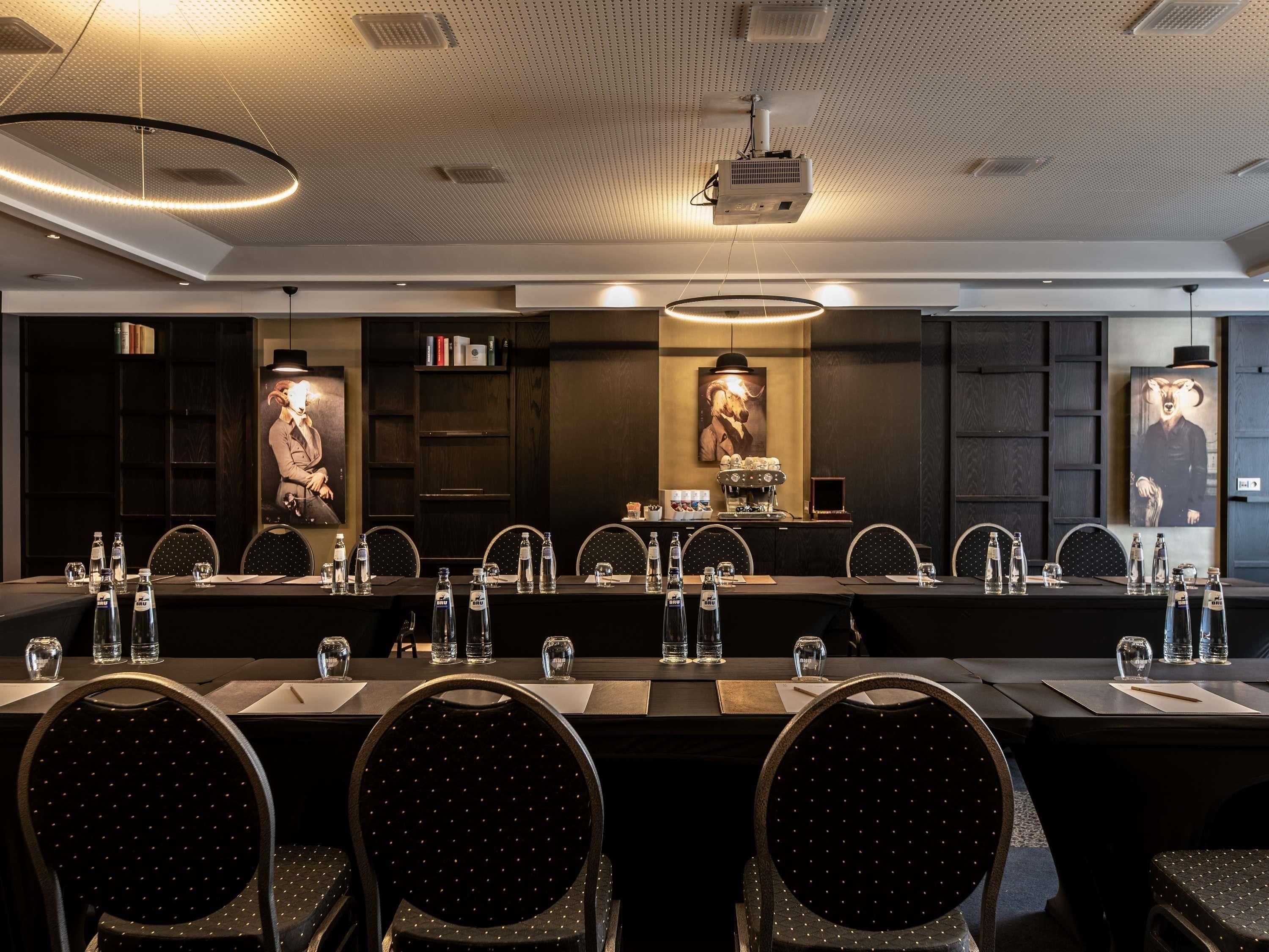 A conference room with a long table, chairs, water bottles, and a coffee machine.