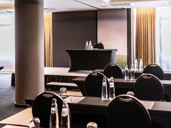 A conference room with a black table, chairs, water bottles, and a podium.