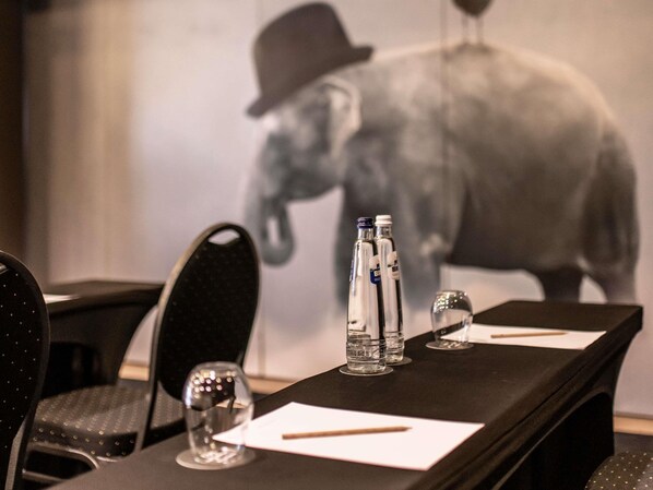 Una mesa de conferencias con botellas de agua, vasos y un bloc de notas.