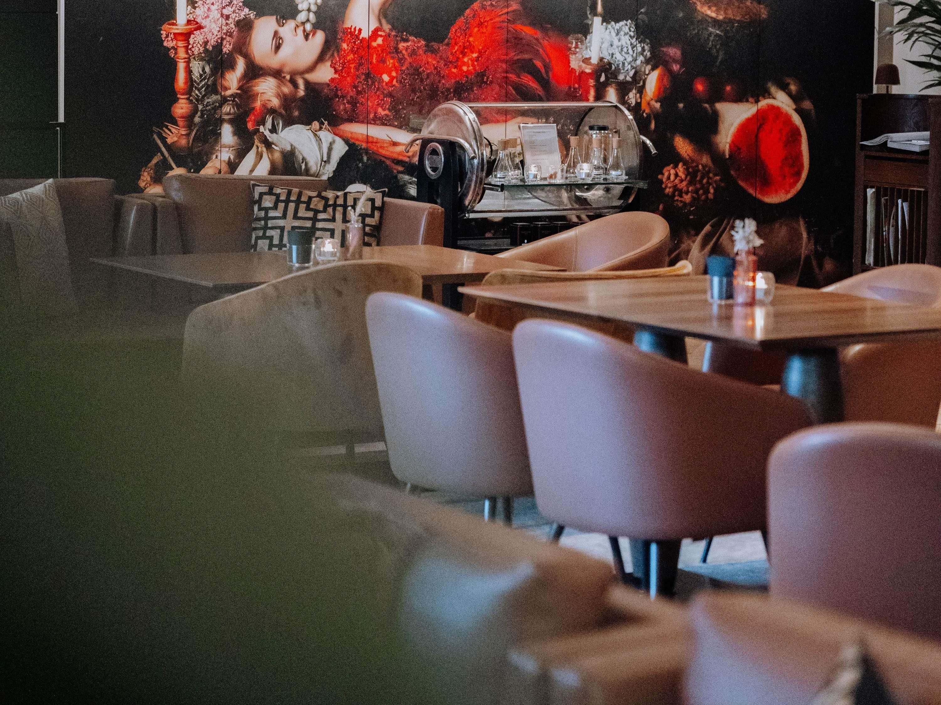 A restaurant interior with a vintage car display, wooden tables, and chairs.