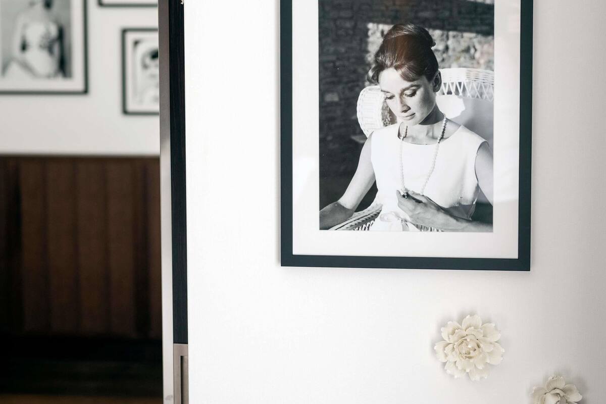 A framed photograph on a wall, a white door, and two white flowers.