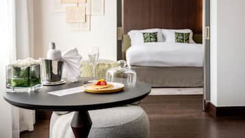 Une chambre d’hôtel avec un lit, une table de chevet sur laquelle se trouvent un verre, une bouteille et une assiette avec de la nourriture.
