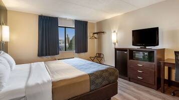 Quarto de hotel com cama, escrivaninha, televisão, minibar e vista para o exterior.