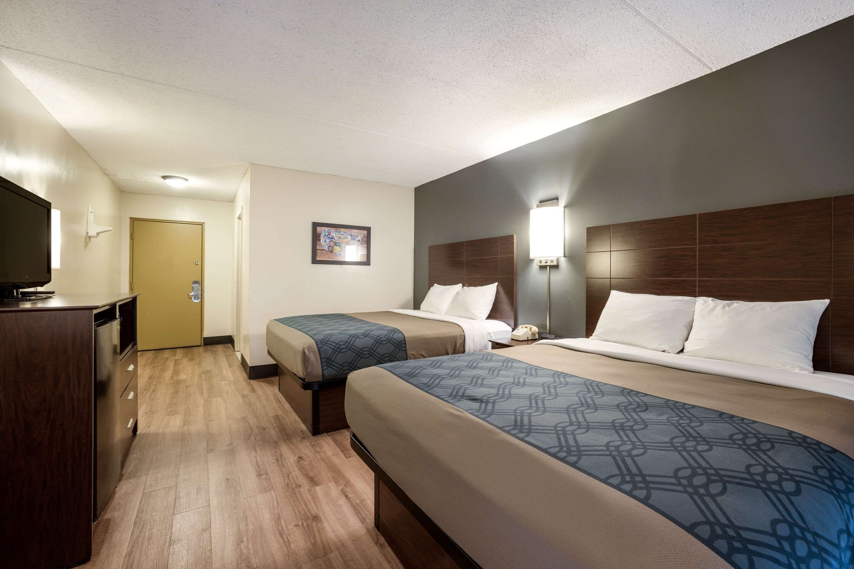 A hotel room with two beds, a TV, a desk, and a bathroom door.