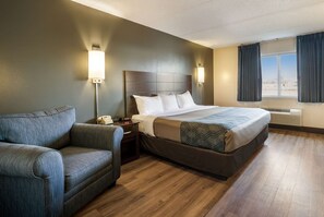 A hotel room with a bed, a sofa, a nightstand with a phone, two wall-mounted lamps, and a window with curtains. - Econo Lodge Darien Lakes (Corfu)