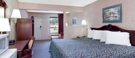 Ein Hotelzimmer mit Bett, Schreibtisch, Stuhl und Blick nach draußen.