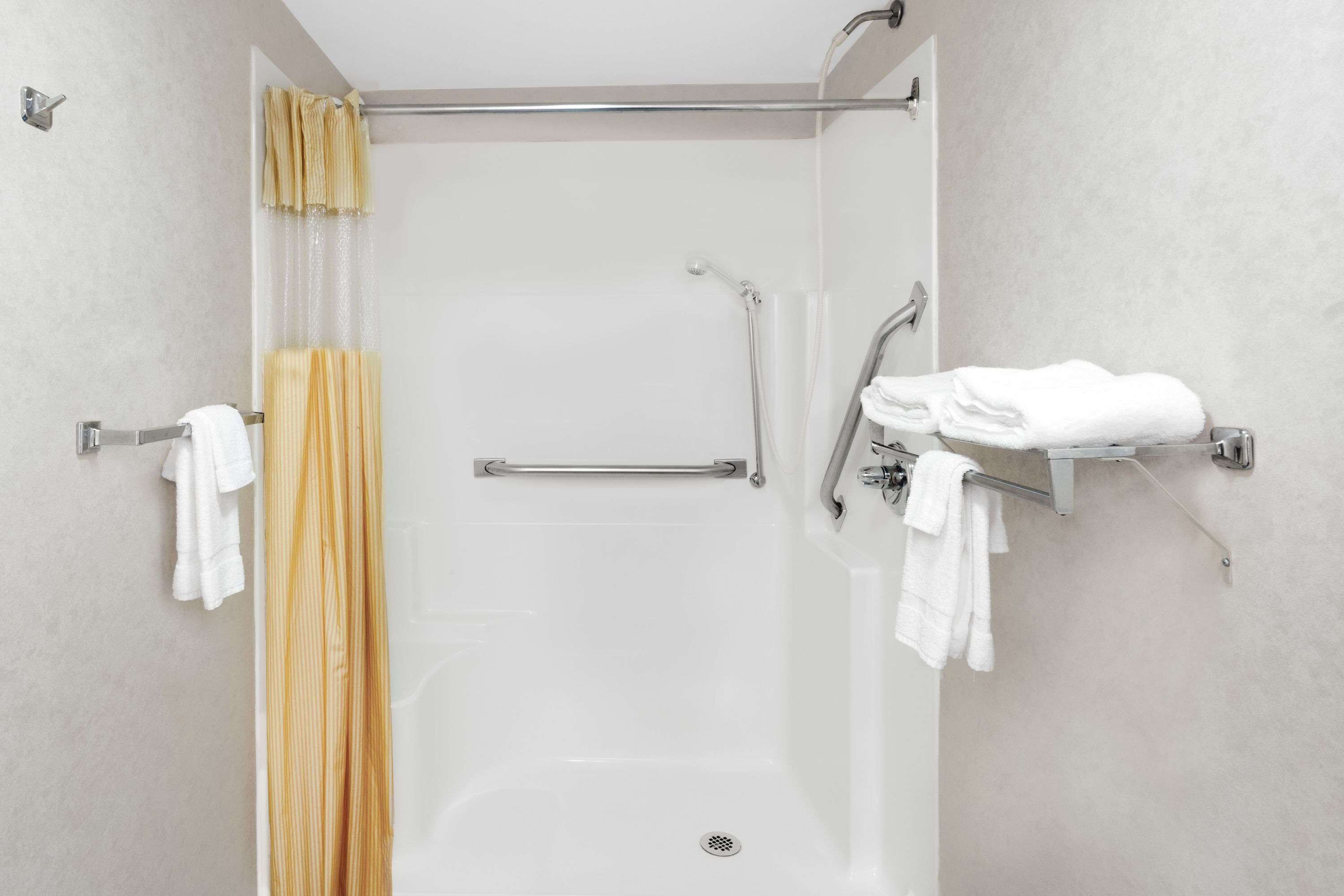 A walk-in shower with a glass door, a towel rack, and a shower curtain.