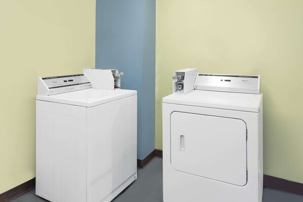 Dos lavadoras frontales blancas en una habitación con paredes amarillo claro y azules.