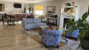 A modern living room with a sofa, armchairs, and a coffee table. There is a kitchen area with a microwave, refrigerator, and a dining table with chairs. - Quality Inn & Suites Prairie Du Chien (Prairie Du Chien)