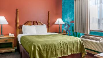 Una habitación de hotel con una cama grande, dos mesitas de noche, un velador, una ventana con cortinas y un mural en la pared.