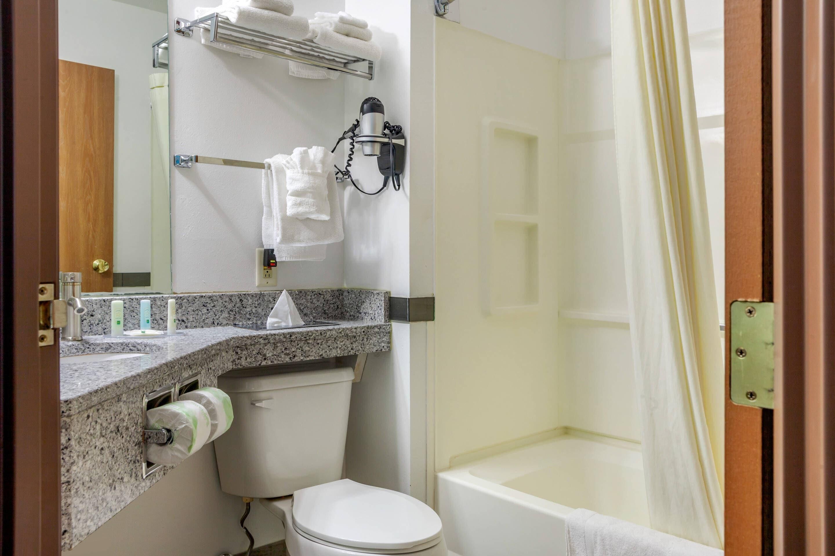 Une salle de bain équipée de toilettes, d’un lavabo, d’un porte-serviettes et d’un rideau de douche.