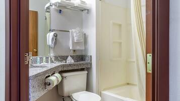 Un baño con inodoro, ducha, lavabo con espejo y toallero.