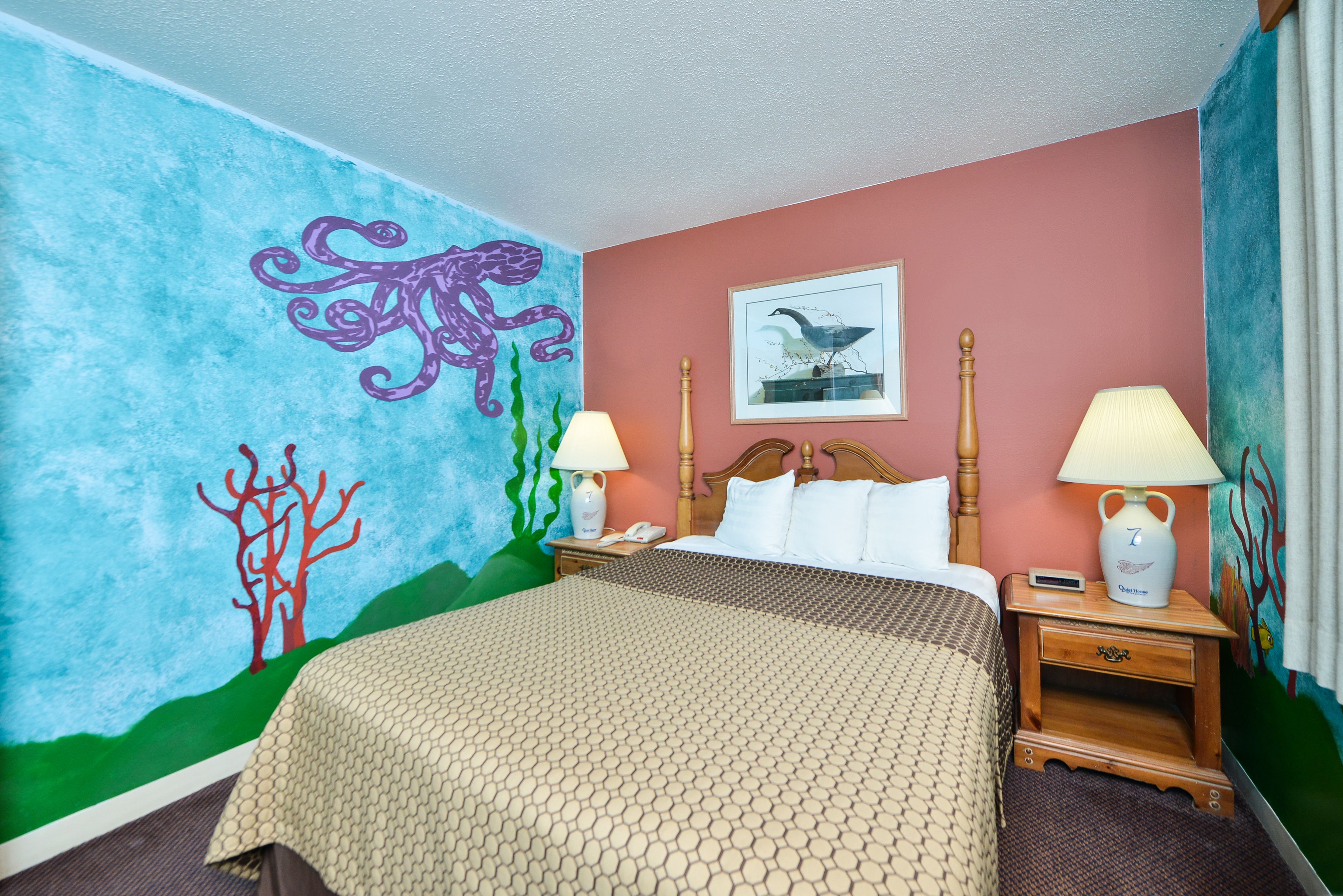 Een hotelkamer met een bed, twee nachtkastjes, een wanddecoratie en een fotolijst aan de muur.