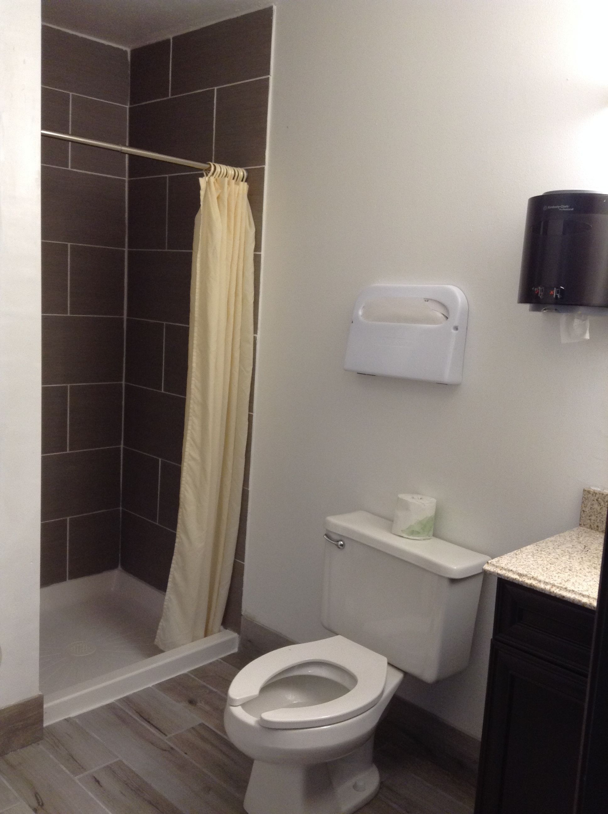 Un baño con ducha, inodoro y secador de manos.