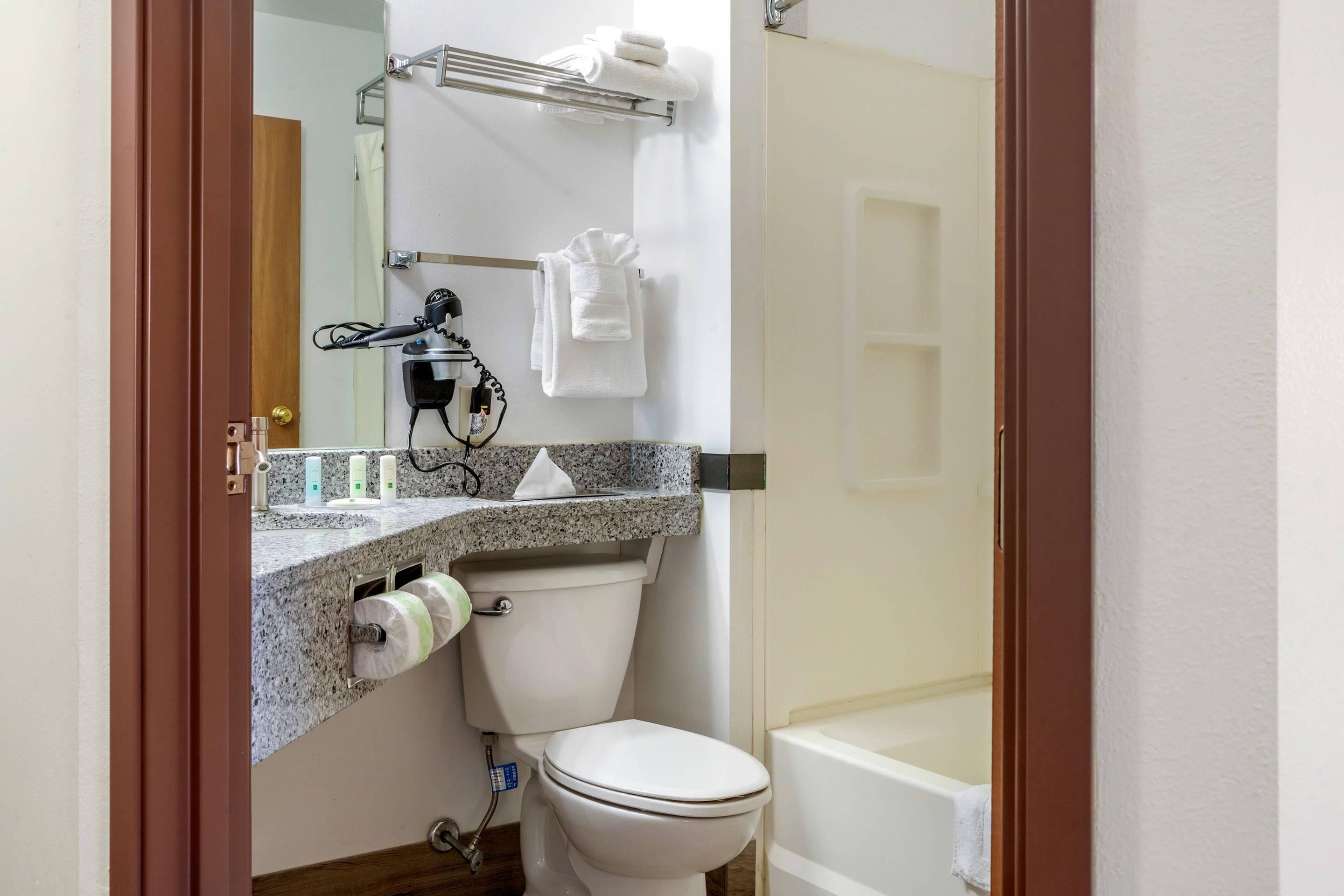 A bathroom with a toilet, sink, towel rack, and a shower area.