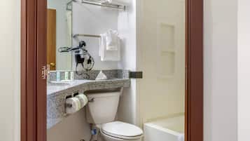 A bathroom with a toilet, sink, towel rack, and a shower area.