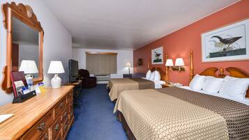 A hotel room with two beds, a dresser, a mirror, a television, and a window with curtains.