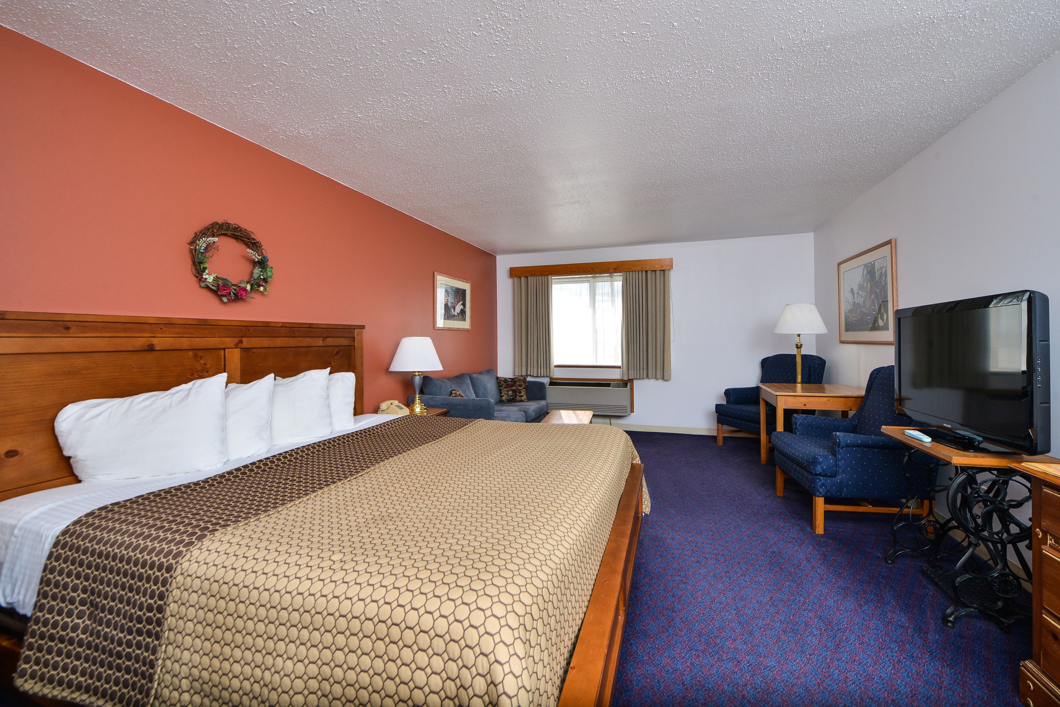 A hotel room with a large bed, a desk with a television, a chair, and a couch.
