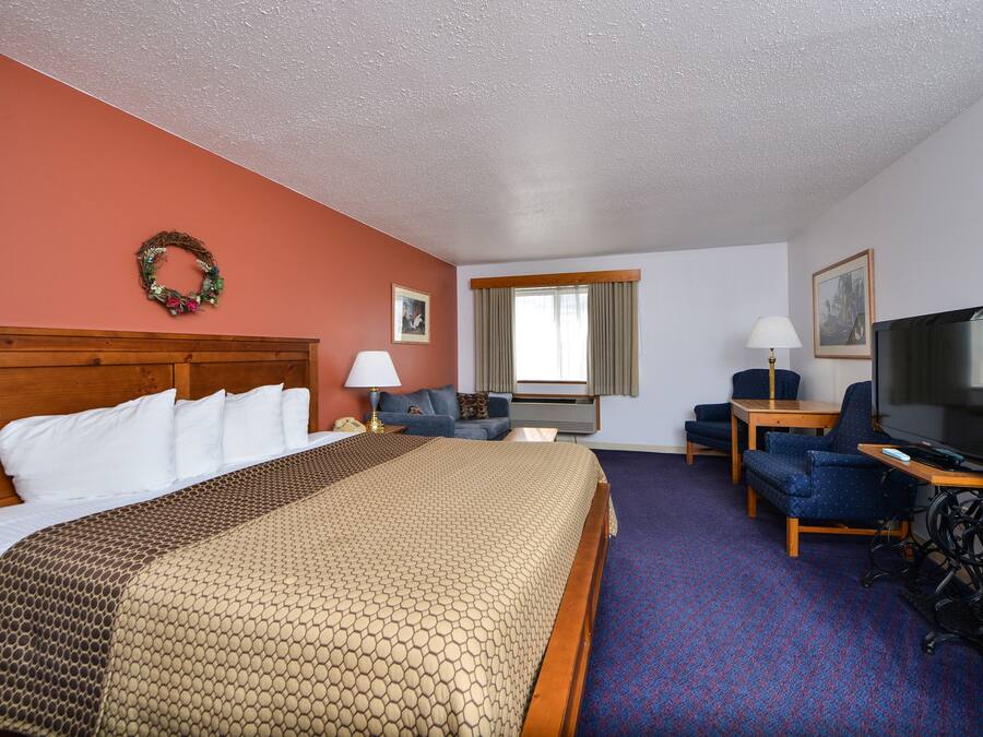 A hotel room with a large bed, a desk with a television, a chair, and a couch.
