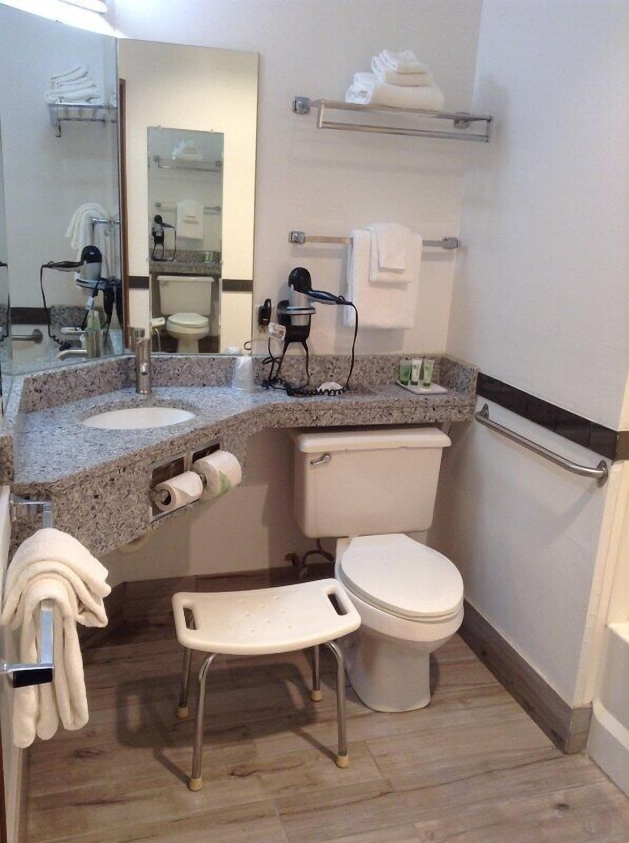Baño pequeño y funcional con lavamanos, inodoro y un taburete.