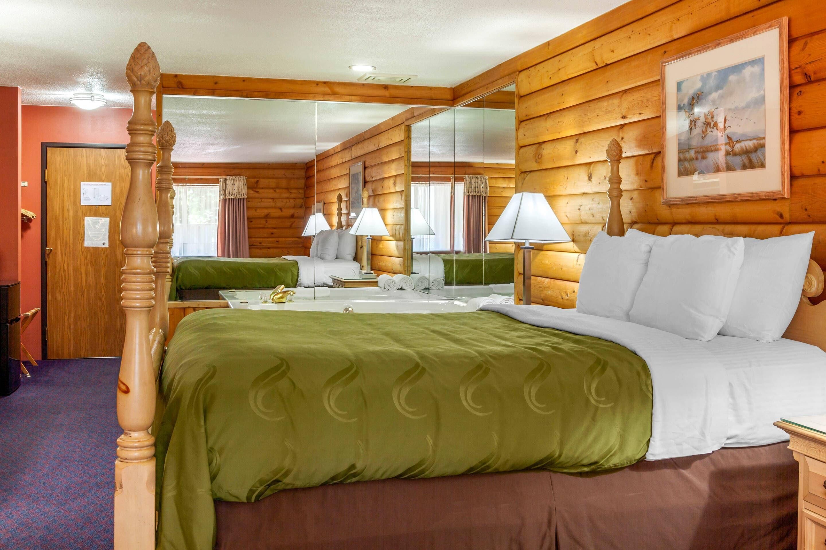 A wooden cabin-style room with a four-poster bed, a mirror, and a painting on the wall.
