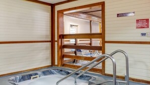 A hot tub with metal steps and a wooden frame, a sign indicating pool access for persons with infectious diseases, and a Whirlpool switch sign. - Quality Inn & Suites Prairie Du Chien (Prairie Du Chien)