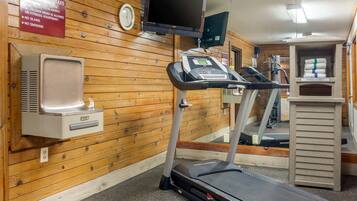 Une salle de sport équipée d’un tapis de course, d’un téléviseur fixé au mur, d’un porte-serviettes et d’un panneau indiquant les règles.