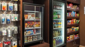 A self-service beverage station with refrigerated drinks and snacks, a coffee machine, and a variety of packaged goods.
