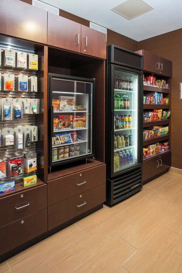 A self-service beverage station with refrigerated drinks and snacks, a coffee machine, and a variety of packaged goods. - Wingate by Wyndham Oshkosh (Oshkosh)