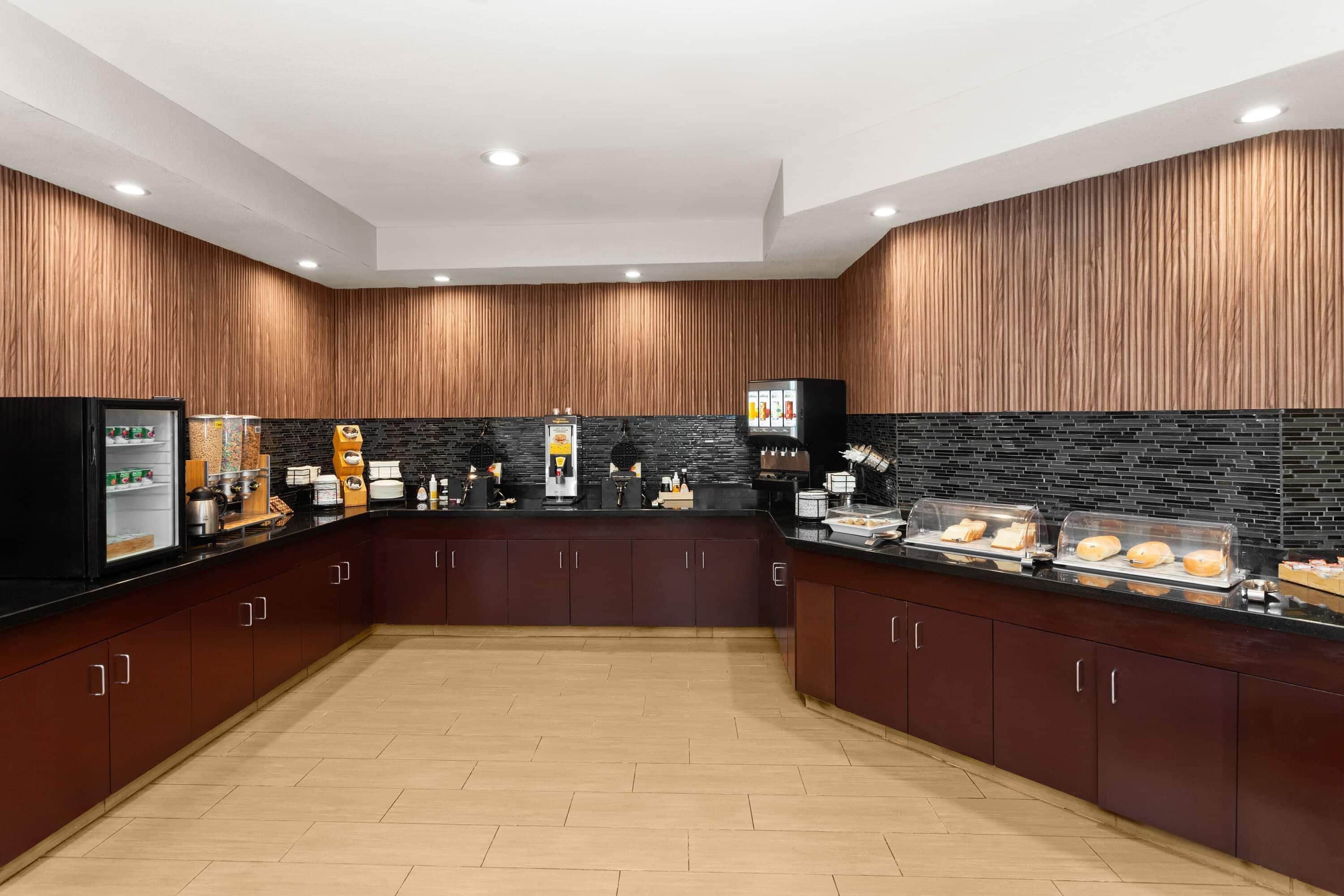 A modern kitchen with wooden paneling, a black countertop, and a tiled backsplash.