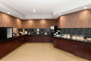 Una cocina moderna con paneles de madera, encimera negra y salpicadero de azulejos.