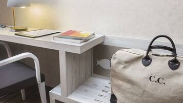A desk with a lamp, a book, and a bag with "C.C." on it.