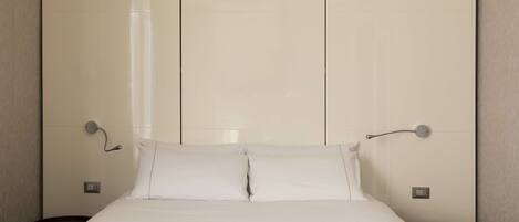 A modern hotel room with a large bed, a bedside table, and a nightstand.