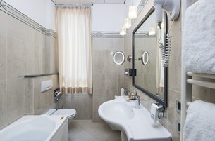 A modern bathroom with a bathtub, two sinks, a mirror, and a towel rack.