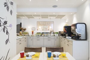 Una cucina moderna con zona pranzo, che include un'area buffet, macchine da caffè e una parete decorativa.