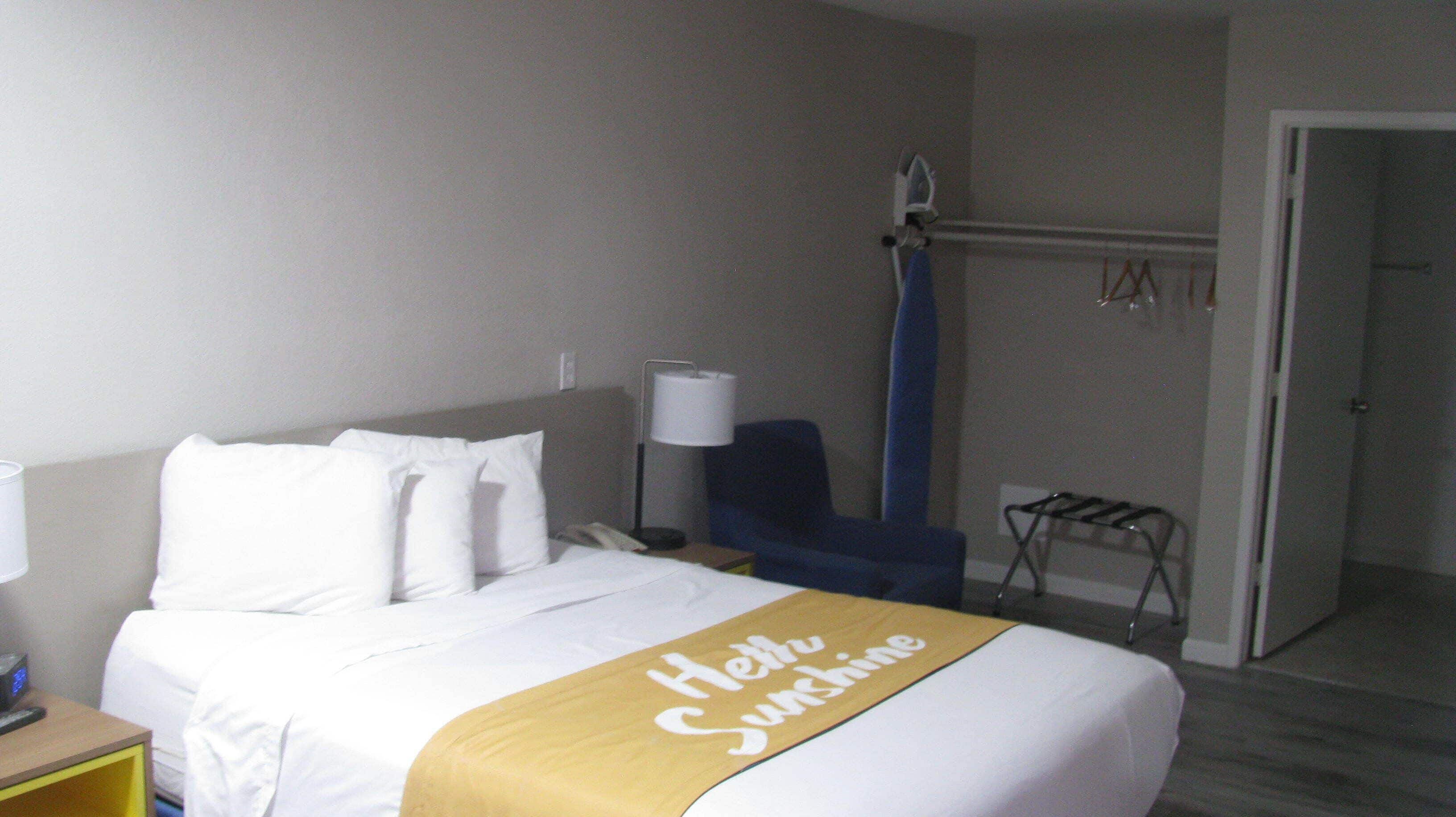 Habitación de hotel con cama, escritorio, silla, zona de ducha y puerta.