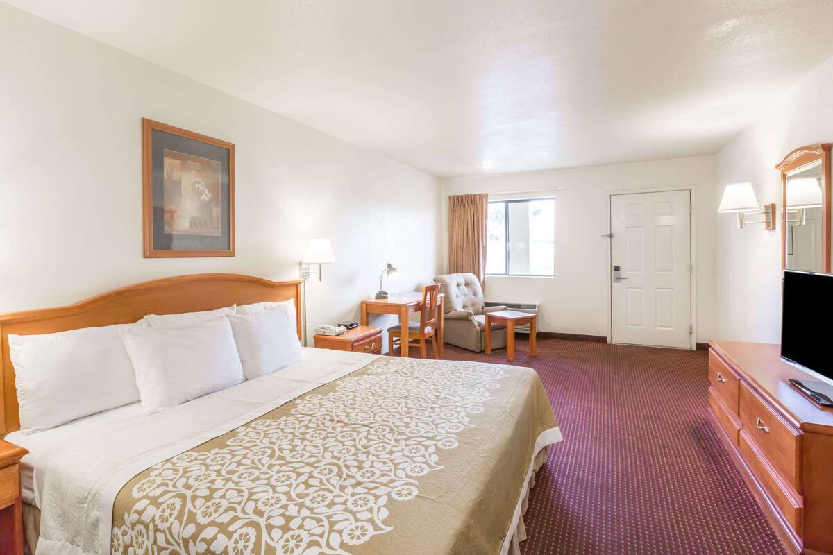 Ein Hotelzimmer mit Bett, Schreibtisch, Stuhl, Fernseher und einer Tür.