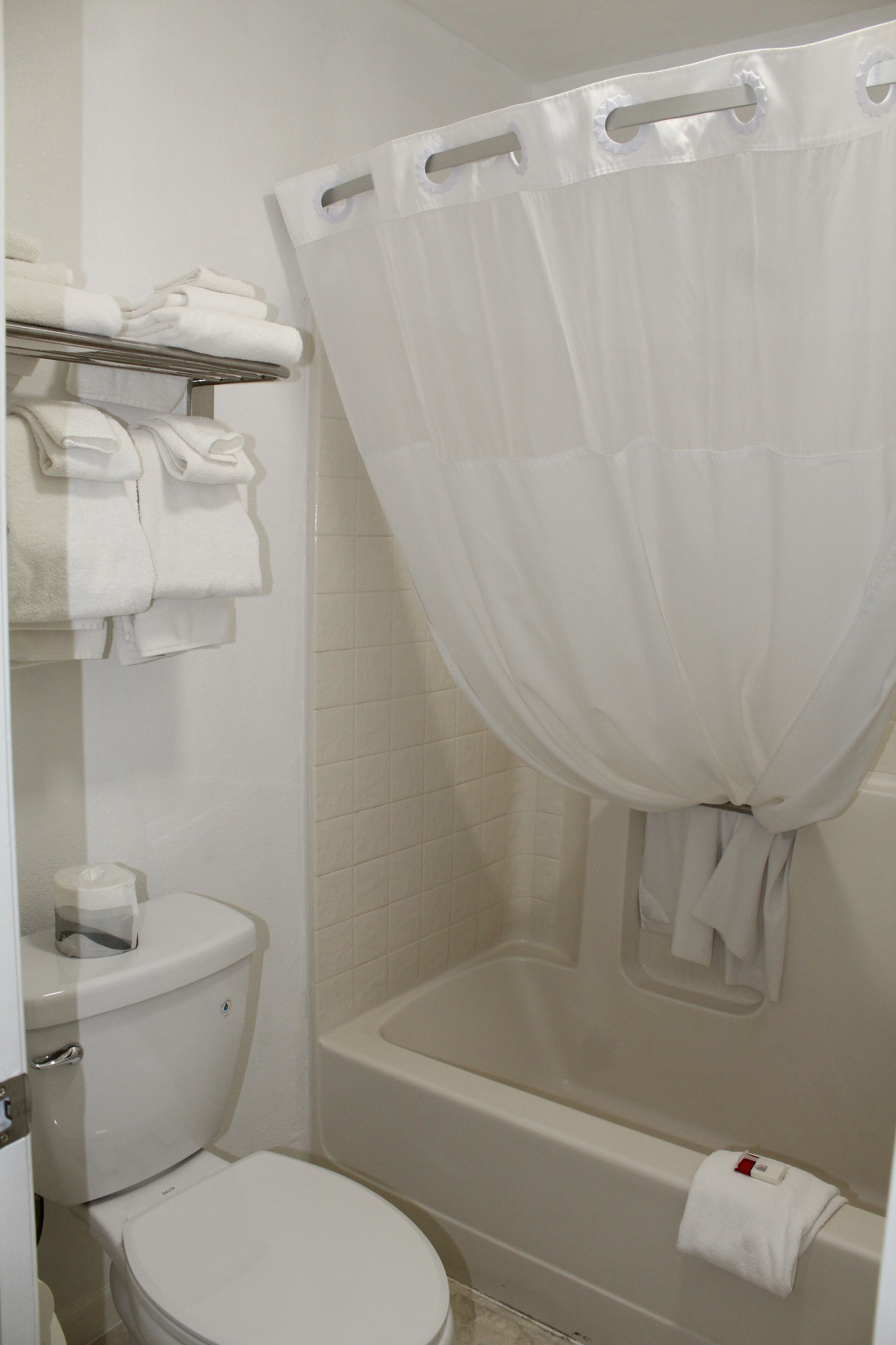 Une salle de bain équipée de toilettes, d’une baignoire et d’un rideau de douche.
