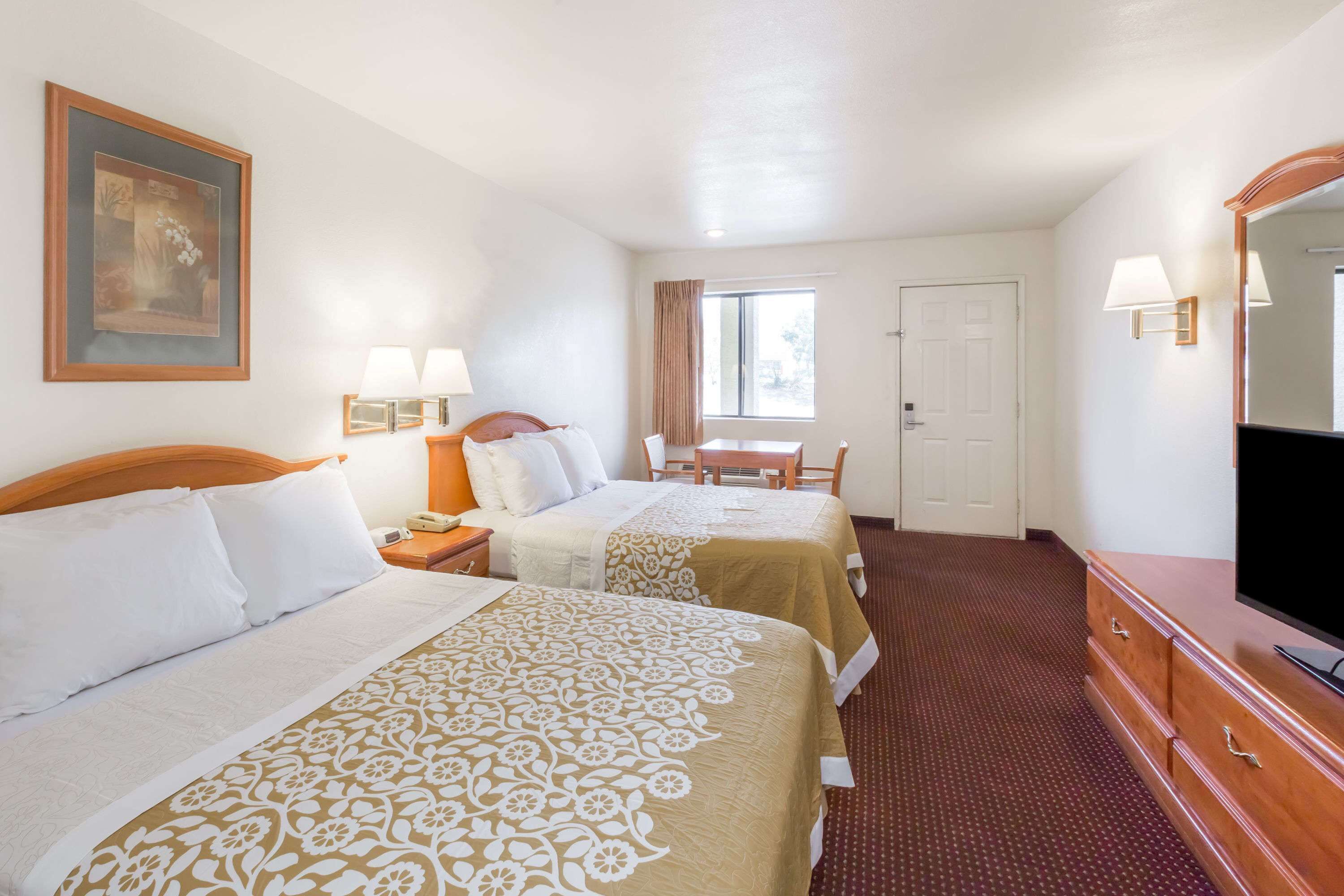 Een hotelkamer met twee bedden, een bureau, een stoel, een dressoir en een televisie.