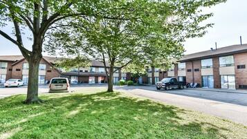 A parking lot with a tree and a building with multiple windows and doors.