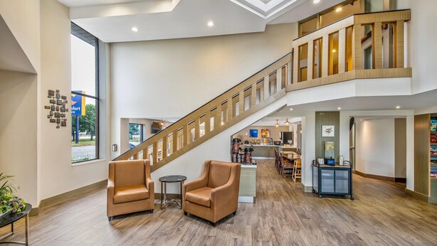 A spacious lobby with a central staircase, seating area, and a reception desk.