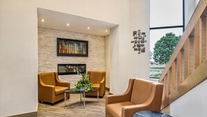 A lobby with a stone wall, a painting, a fireplace, and a staircase.