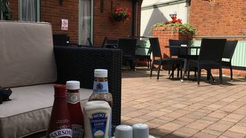 A table with a plate of French fries, bottles of condiments, and salt and pepper shakers outside a building with a sign reading "GEORGE HOTEL".