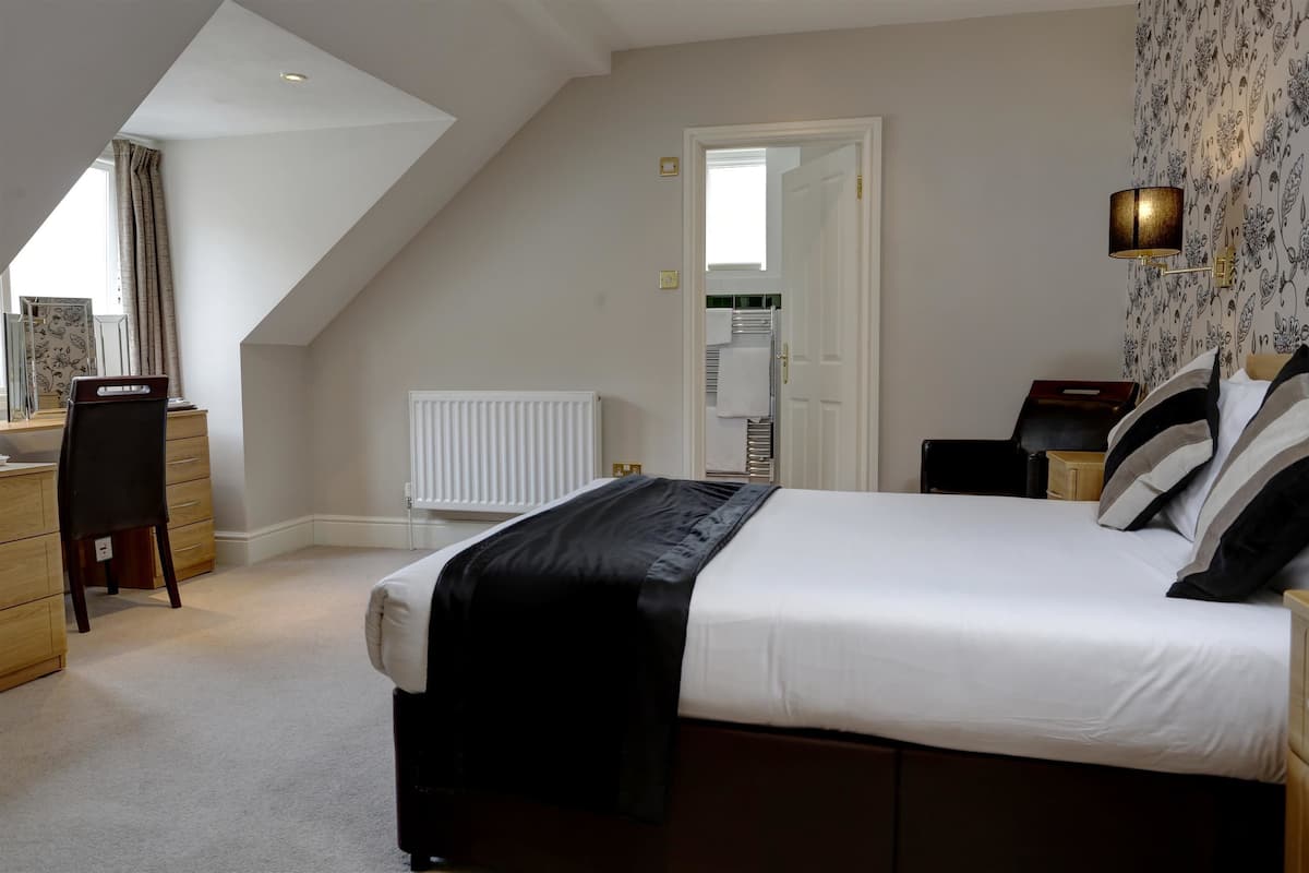 Une chambre avec un grand lit, un bureau et un radiateur.