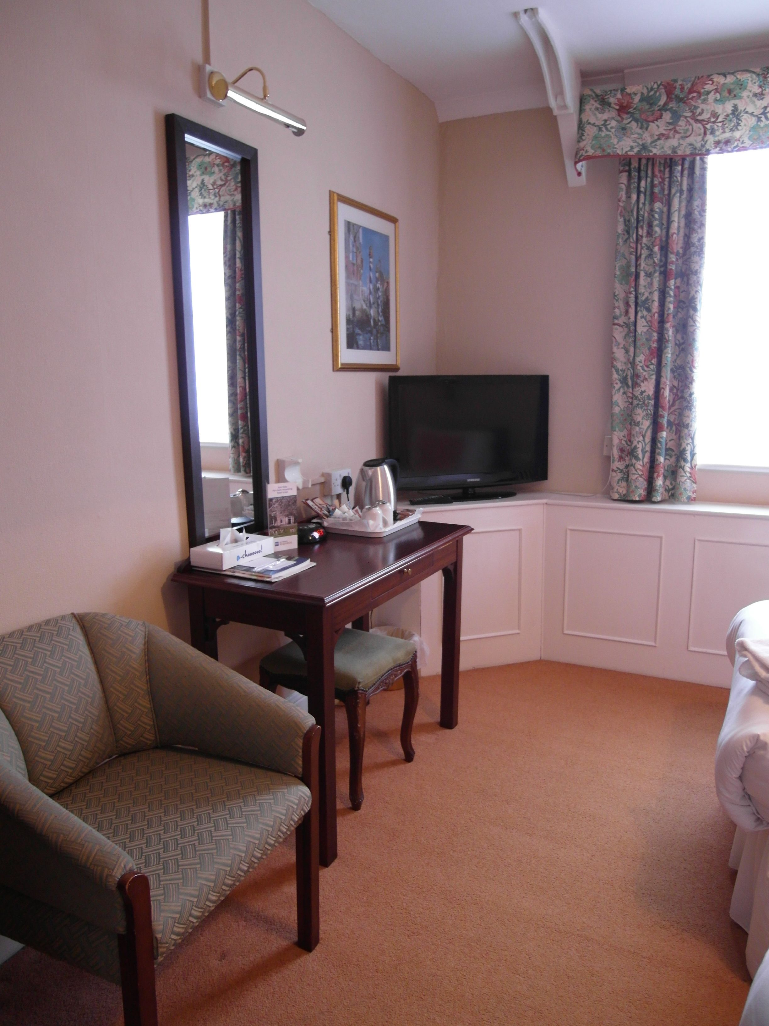 Una habitación de hotel con escritorio de madera, televisión, silla y cama.