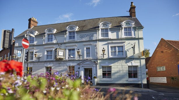 A George Hotel with a traditional facade, multiple windows, and a sign for 'FEDLARS SUNDAY CARVERY' on the side.